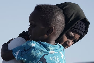A Sudanese evacuee carries her son as they arrive at Jeddah in Saudi Arabia. AP