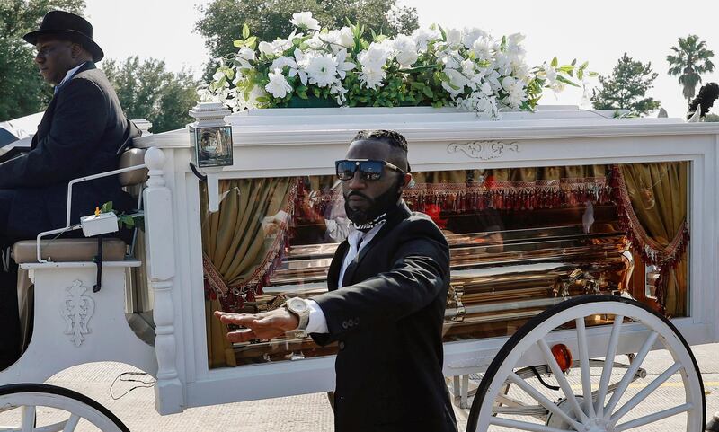 A man holds his hand up in solidarity as the body of George Floyd is brought by horse-drawn carriage in a funeral procession to Houston Memorial Gardens Cemetery for burial in Pearland, Texas. Getty Images