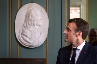 French President Emmanuel Macron walks into a room with a relief bust  of French author and philosoper Francois-Marie Arouet, known as Voltaire (1694-1778), during a visit of the newly restored Chateau de Ferney-Voltaire following a ceremony for its reopening, in Ferney-Voltaire, eastern France, on May 31, 2018. - Ferney-Voltaire Castle reopens after three years of renovation. French author and philosopher Voltaire, who died 240 years ago, spent the last 20 years of his life at the castle. (Photo by Fabrice COFFRINI / AFP)