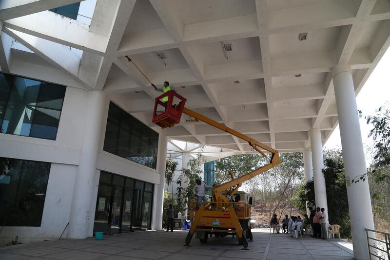 An Indian municipal worker cleans an athletic stadium building where rooms are being prepared to be used as isolation wards in Hyderabad. AP Photo