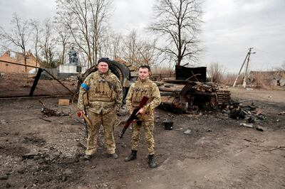 Ukrainian servicemen pose in front of what they say are destroyed Russian military vehicles and equipment in the village of Lukianivka, which they reclaimed from Russian forces. Reuters