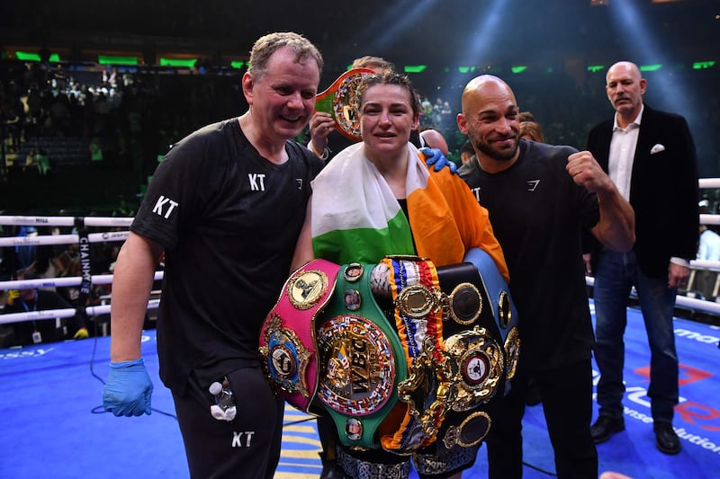 Katie Taylor celebrates with her belts alongside manager Brian Peters and coach Ross Enamait. AFP