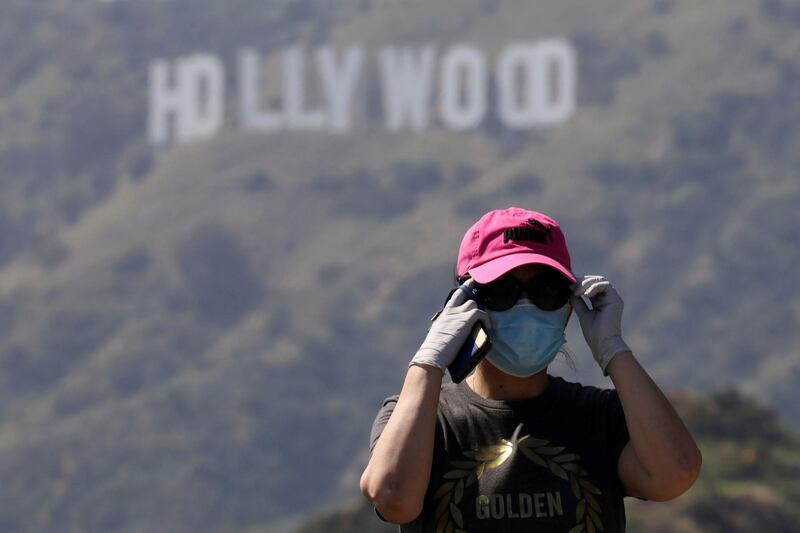 FILE PHOTO: A person wearing a face mask and gloves adjusts glasses while taking photos of the Hollywood sign after a partial reopening of Los Angeles hiking trails during the outbreak of the coronavirus disease (COVID-19) at Griffith Park in Los Angeles, California, U.S., May 9, 2020. REUTERS/Patrick T. Fallon/File Photo