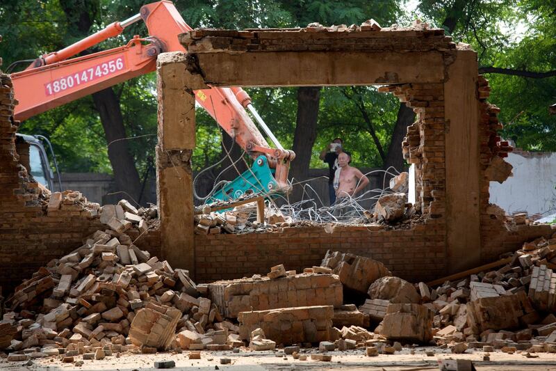 Workers watch as Chinese artist Ai Weiwei's studio is demolished in Beijing, China. Ng Han Guan / AP Photo