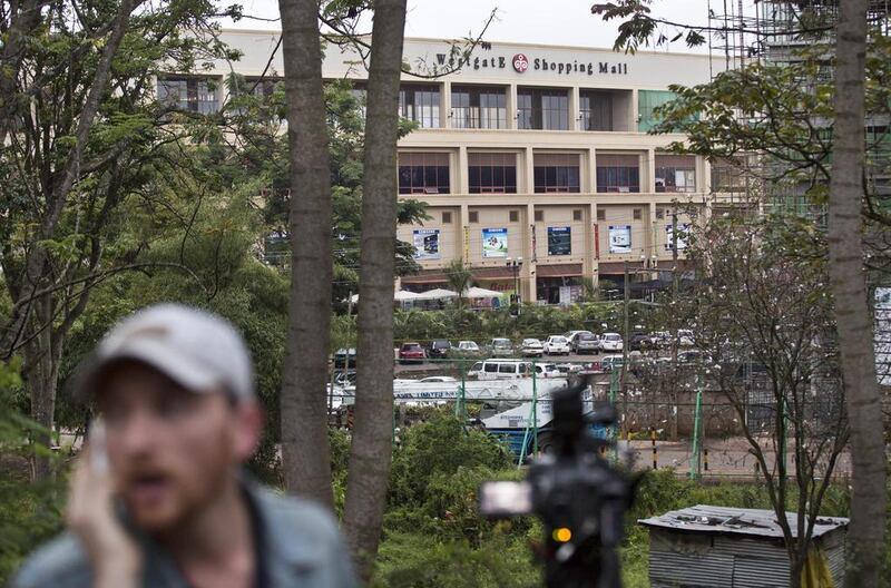 A television reporter makes a telephone call while filming during a bout of heavy gunfire shortly after dawn, at the Westgate Mall in Nairobi, Kenya. AP Photo/Ben Curtis