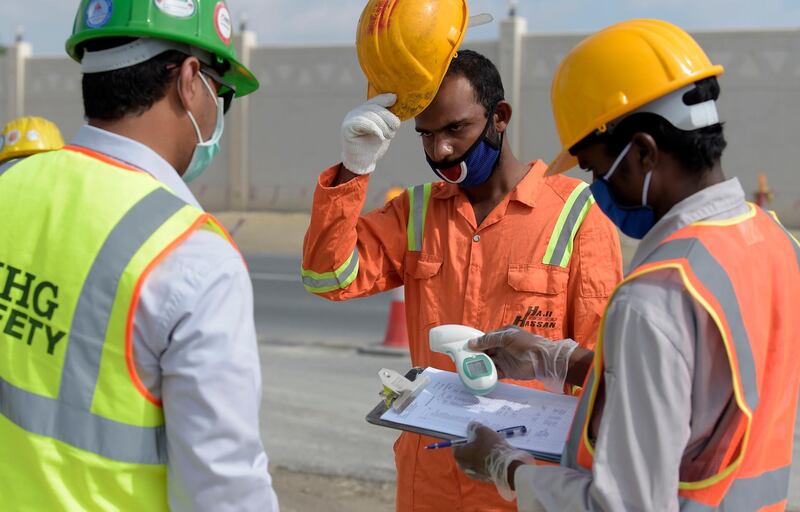 Expatriate workers have their temperatures checked while carrying out road project development in Aali village south of the Bahraini capital Manama. AFP