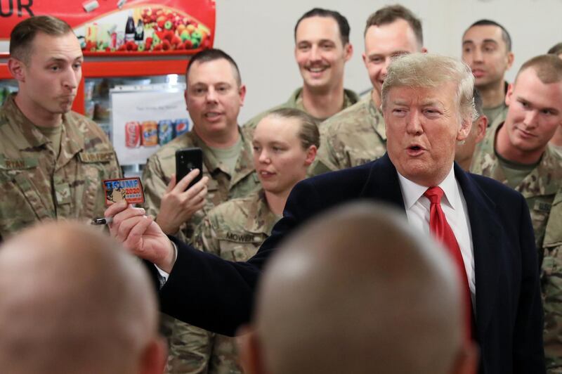 US President Donald Trump holds up a 'Trump 2020' patch an airman asked him to sign as he greets military personnel at the dining facility during an unannounced visit to Al Asad Air Base, Iraq. Reuters