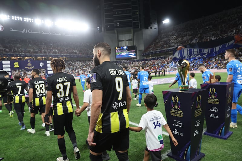 Al Ittihad's Karim Benzema walks out with a young mascot before the match. Reuters 