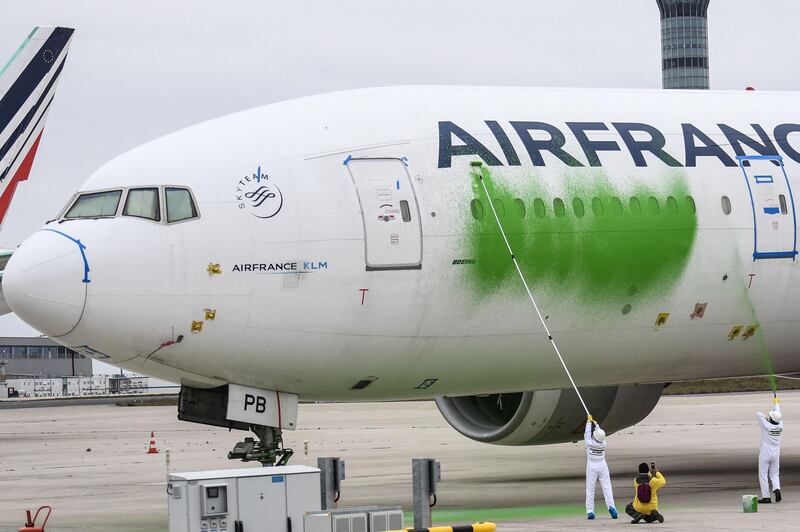 Members of Greenpeace protest calling for the reduction of air traffic in the face of climate challenges, by painting an Air France passenger aircraft parked on the tarmac 'green' at the Roissy-Charles de Gaulle International airport (CDG), north of Paris on March 5, 2021. / AFP / Alain JOCARD
