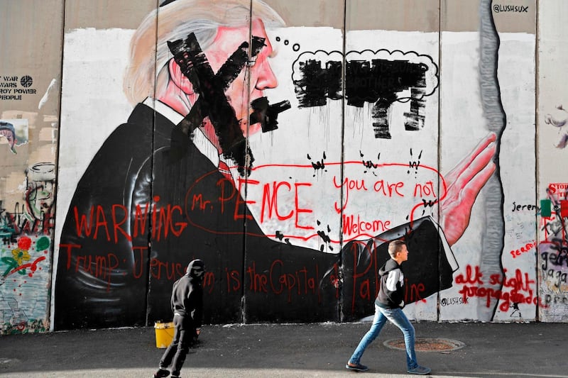 Palestinian children walk past vandalised graffiti depicting US President Donald Trump and slogans against US Vice President Mike Pence painted on Israel's controversial separation barrier in the West Bank city of Bethlehem during clashes with Palestinian protestors near an Israeli checkpoint on December 7, 2017.
US President Donald Trump's recognition of Jerusalem as Israel's capital may bring little immediate concrete change but risks sparking another round of violence in a conflict that has lasted decades. / AFP PHOTO / THOMAS COEX