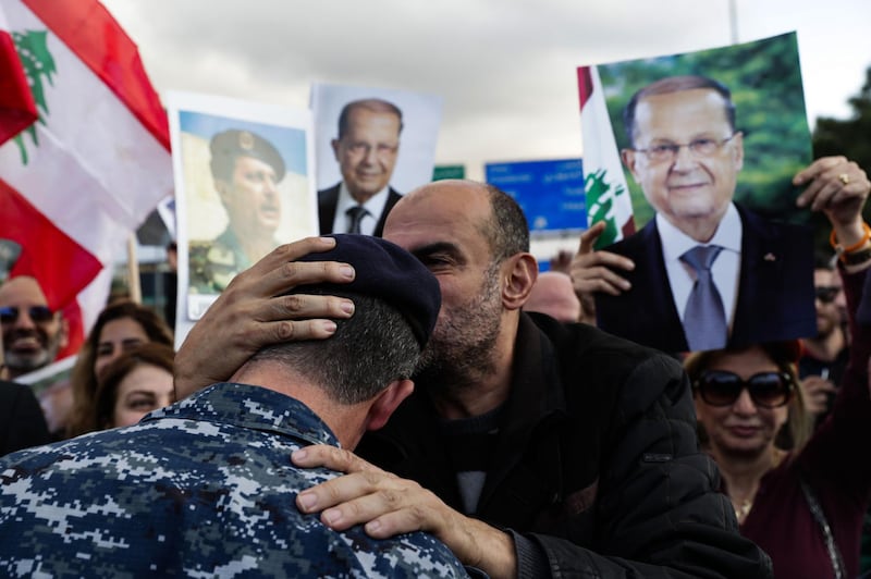 A backer of the Free Patriotic Movement founded by Lebanese President Michel Aoun (pictures), kisses the head of a policeman as he takes part in a rally on a road leading to the presidential palace in Baabda near the capital Beirut. AFP