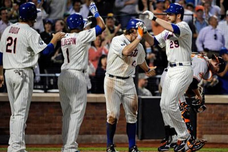 New York Mets' Ike Davis, right, is greeted by R.A. Dickey and Jordany Valdespin (1) and Lucas Duda (21) after Davis hit a grand slam during the sixth inning of an interleague baseball game against the Baltimore Orioles, Monday, June 18, 2012, at Citi Field in New York. (AP Photo/Bill Kostroun)