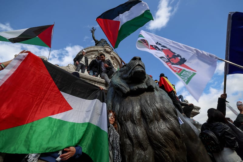 Protestors wave Palestinian flags as they climb on the Monument a la Republique during a demonstration in Paris. AFP