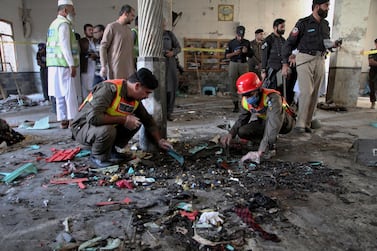 Rescue workers and police officers examine the site of bomb explosion in an Islamic seminary in Peshawar, Pakistan, Tuesday, Oct. 27, 2020. A powerful bomb blast ripped through an Islamic seminary on the outskirts of the northwest Pakistani city of Peshawar on Tuesday morning, killing some students and wounding dozens others, police and a hospital spokesman said. (AP Photo/Muhammad Sajjad)