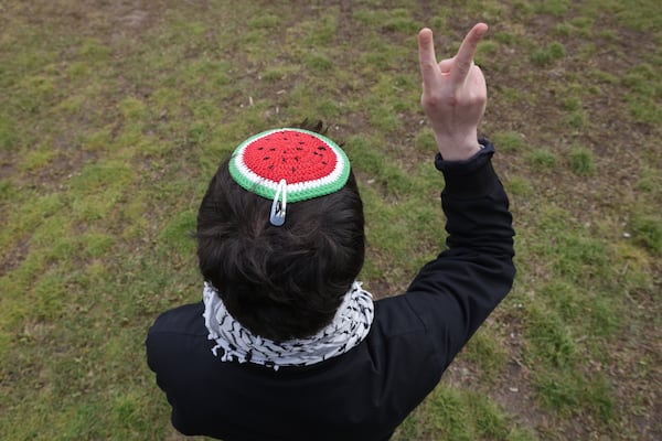 A protester wearing a watermelon yarmulke and a keffiyeh makes a peace sign at a protest in Berlin, Germany. Getty Images