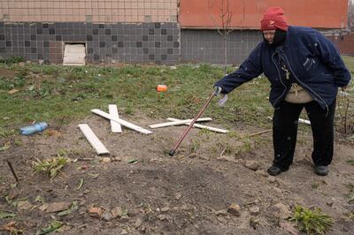 A woman points to a makeshift grave of a man who residents of Bucha say was killed by Russian forces. AP 