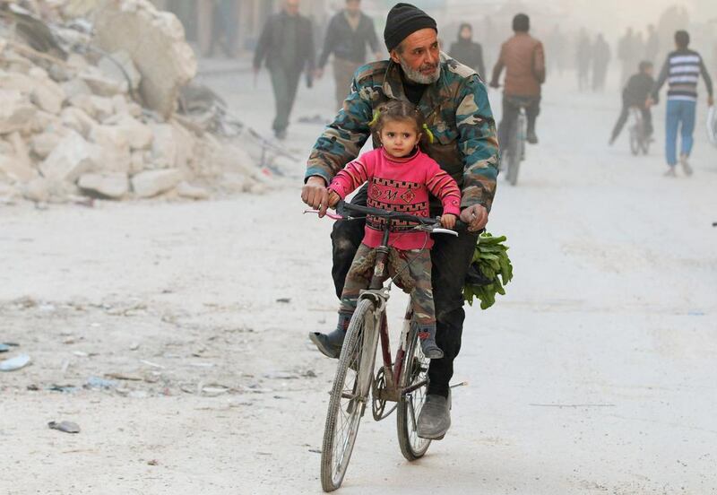 A man cycles with his daughter in a rebel-held area of besieged eastern Aleppo on November 23, 2016. Abdalrhman Ismail / Reuters