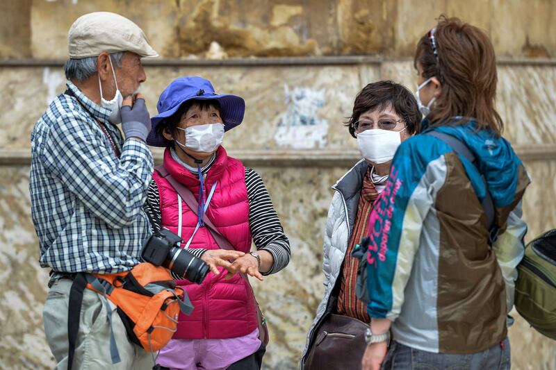 Tourists wearing protective health masks wait outside al-Hussein mosque in the Islamic Cairo district of the Egyptian capital on March 13, 2020.  / AFP / Ahmed HASAN
