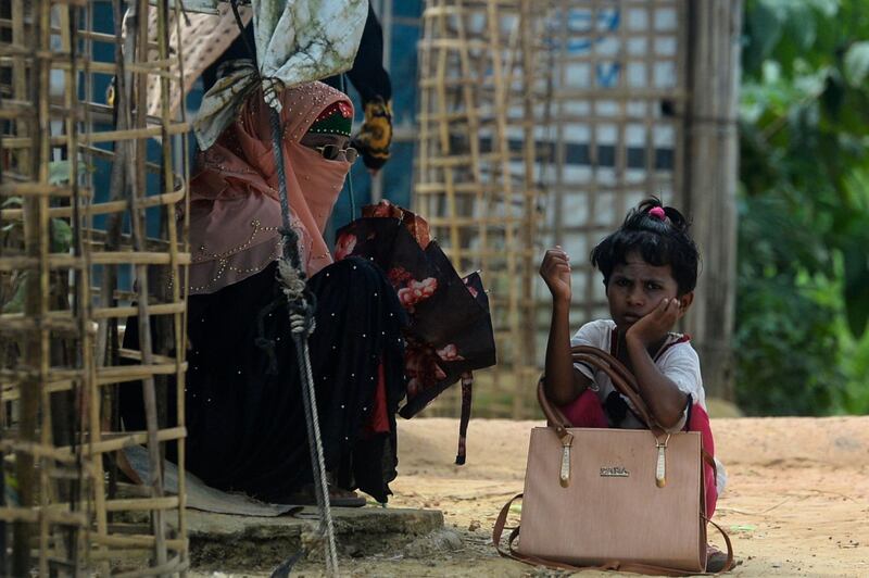 A Rohingya refugee girl waits for transportation with her mother at Kutupalong refugee camp in Ukhia on October 15, 2020. / AFP / Munir Uz Zaman
