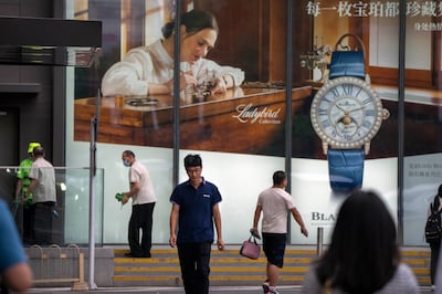 People walk past a billboard for Swiss luxury watch retailer Blancpain at a shopping mall in Beijing. AP