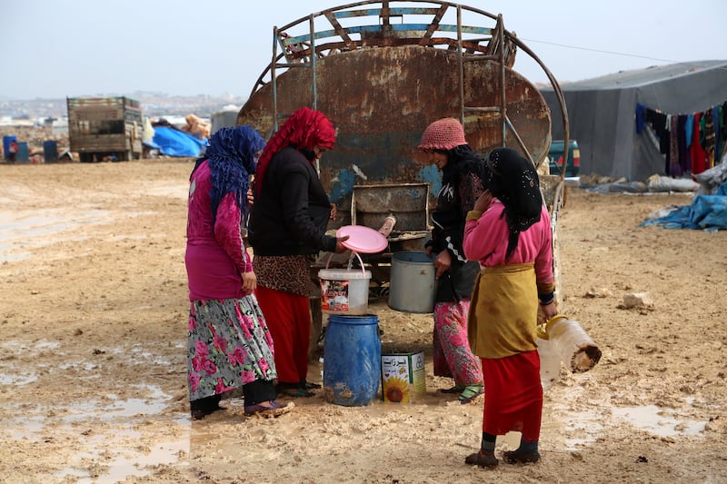 epa06421121 Internally displaced women fill their jerrycans with water at the Kalbeed makeshift camp, near Bab al-Hawa crossing by the Syrian-Turkish border, 06 January 2018. Hundreds of families fled the fighting between government and opposition forces around Idlib.  EPA/ZEIN ALRIFAII