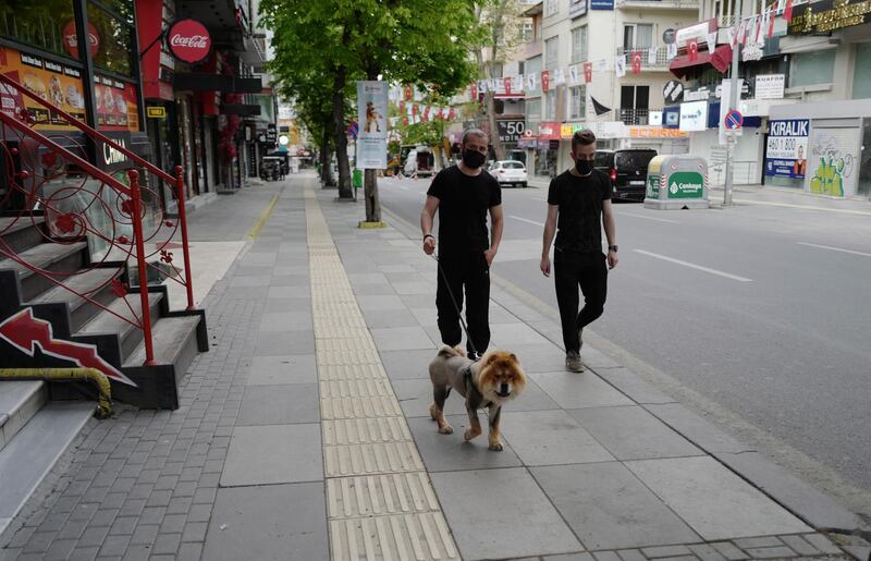 People walk on a nearly deserted street in the Turkish capital, Ankara. Turkish security forces are patrolling main streets and have set up checkpoints at entry and exits points of cities to enforce Turkey's strictest Covid-19 lockdown so far. AP