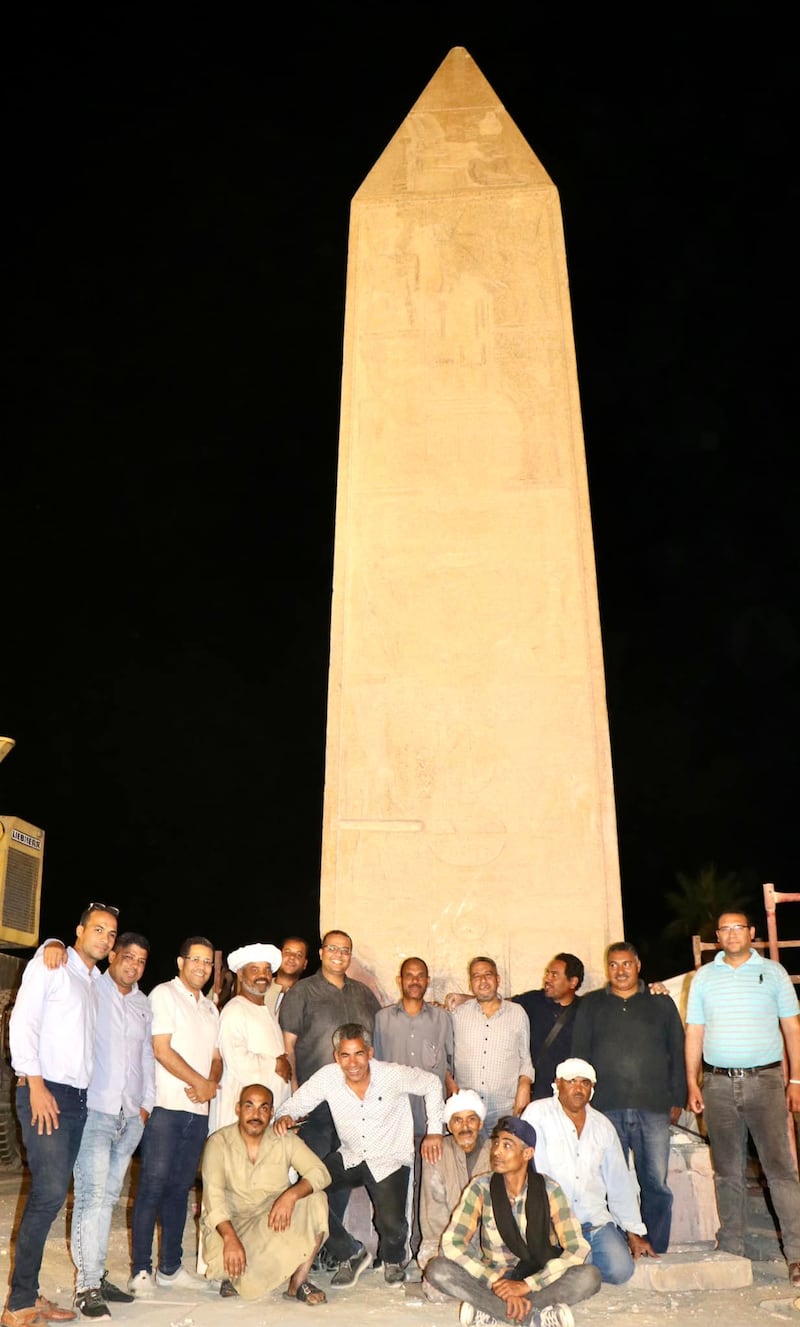 A team of Egyptologists pose for a photo in front of the newly re-erected obelisk of Hatshepsut at Luxor's Karnak Temple. The obelisk had been brought down by an earthquake in antiquity, leaving just over a third of the original obelisk intact.