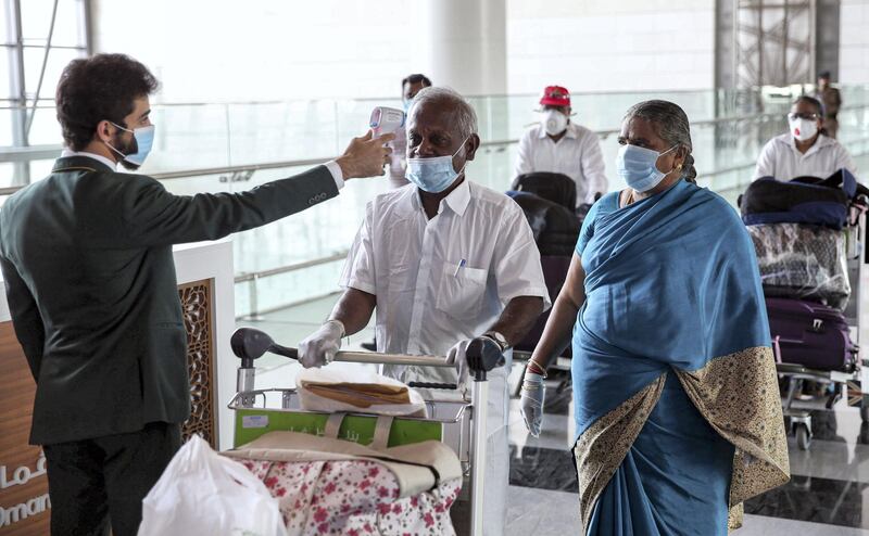 Indian nationals residing in Oman, wearing face masks due to the COVID-19 coronavirus pandemic, have their body temperatures measured at a terminal in Muscat International Airport ahead of their repatriation flight from the Omani capital, on May 12, 2020. (Photo by MOHAMMED MAHJOUB / AFP)