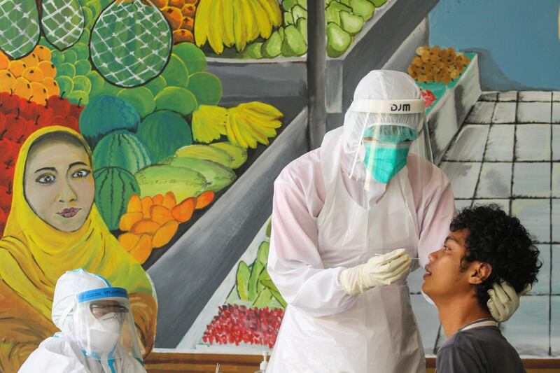 Healthcare workers take a swab sample from a vendor at a traditional market amid the Covid-19 outbreak, in Depok, near Jakarta, Indonesia, May 16. Antara Foto / Asprilla Dwi Adha via Reuters