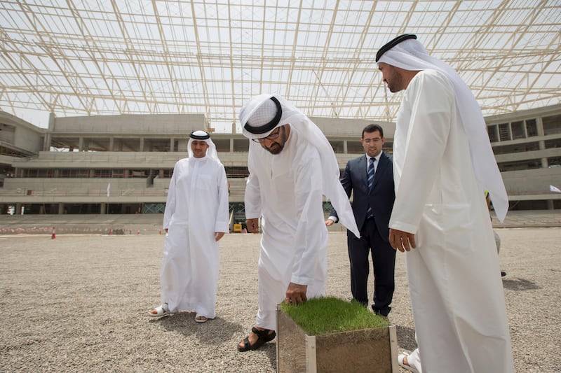 AL AIN, EASTERN REGION OF ABU DHABI, UNITED ARAB EMIRATES - May 08, 2013: HH General Sheikh Mohamed bin Zayed Al Nahyan Crown Prince of Abu Dhabi Deputy Supreme Commander of the UAE Armed Forces (2nd L), looks at a turf sample while inspecting the construction of the Hazza Bin Zayed Stadium, which will serve as the new home ground of Al Ain Football Club. Seen with HE Khalid Abdullah bin Shaiban Al Mehairi Director General of the Executive Council (back L), Kareem Nagy Hassan CEO of Al Qattara Investments (back 3rd L), and HE Mohamed Mubarak Al Mazrouei Under-Secretary of the Crown Prince Court of Abu Dhabi (R). .( Ryan Carter / Crown Prince Court - Abu Dhabi ).--