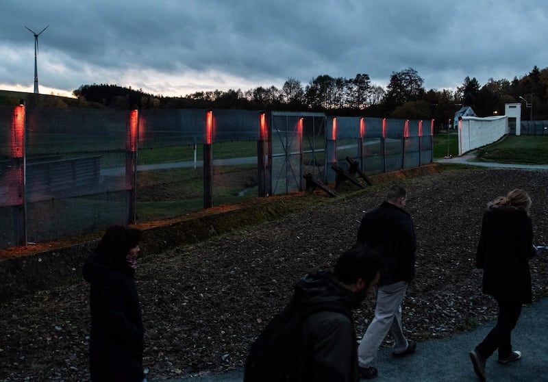 Visitors pass by illuminated border fence at former east German-west German borderline, part of German museum in Moedlareuth, Germany. EPA