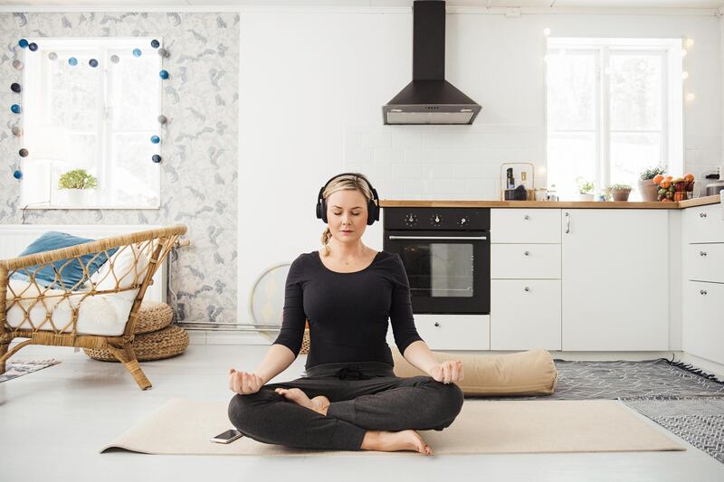 Real woman at home in kitchen doing yoga and meditation. Getty Images