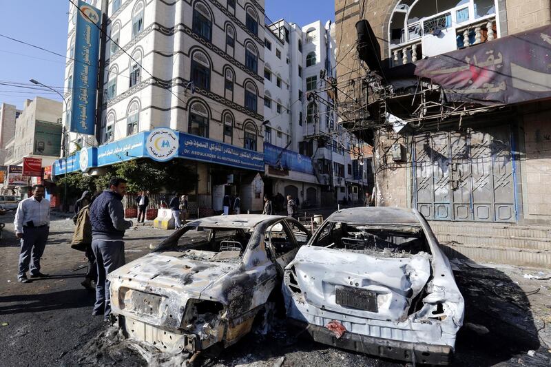 Yemenis walk past destroyed vehicles at a street leading to the residence of Yemen’s ex-president Ali Abdullah Saleh a day after Houthi militants killed him, in Sana’a, Yemen. Yahya Arhab / EPA
