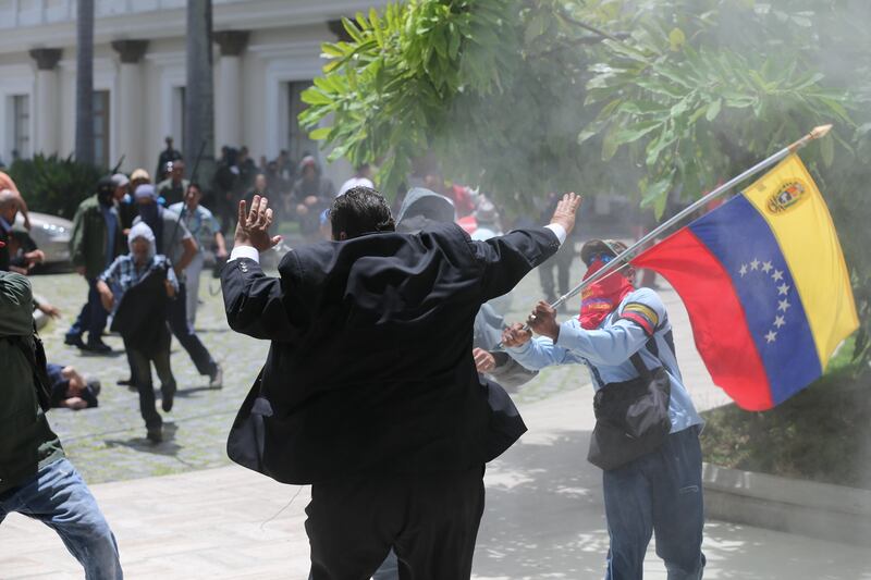 Opposition lawmaker Franco Casella is attacked by masked men in a melee with supposed government supporters who tried to forced their way into the National Assembly at the end of a ceremony commemorating the country's Independence Day in Caracas, Venezuela, Wednesday, July 5, 2017. Venezuela is marking 206 years of their declaration of independence from Spain.  (AP Photos/Fernando Llano)