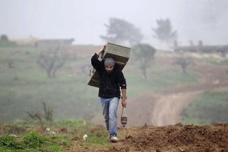 A man carries a weapons box left behind by forces loyal to Syria’s President Bashar al-Assad at the Azaalana checkpoint, after rebels took control of two military posts from the forces, in the southern Idlib countryside. Khalil Ashawi / Reuters