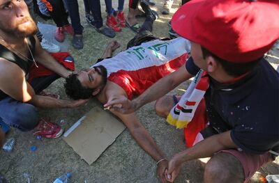 TOPSHOT - Iraqi men try to help a wounded protester during a demonstration against state corruption, failing public services, and unemployment, in the Iraqi capital Baghdad's central Khellani Square on October 4, 2019. Iraqi security forces said "unidentified snipers" killed four people across the capital Baghdad today, the fourth day of violent anti-government protests. / AFP / AHMAD AL-RUBAYE
