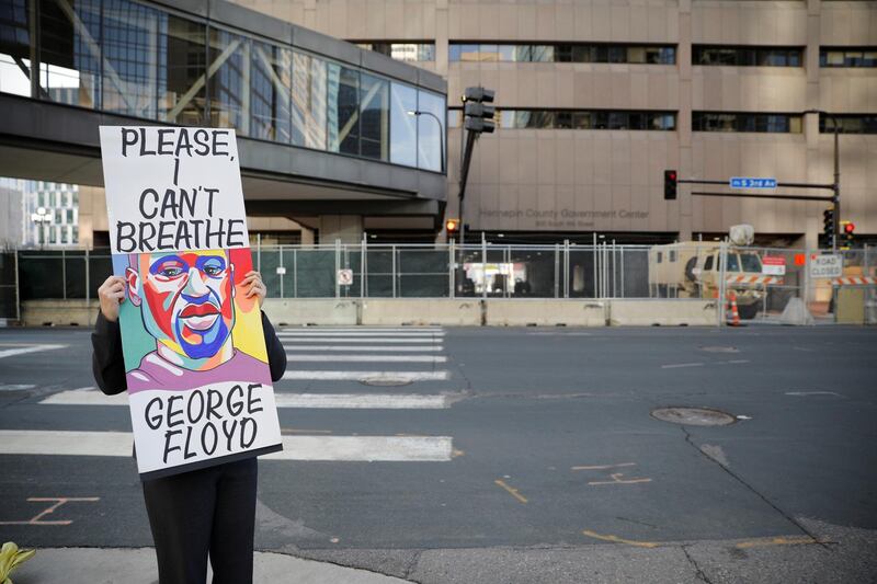 An activist holds a sign outside the Hennepin County Government Center on the seventh day in the trial of former police officer Derek Chauvin, who is facing murder charges in the death of George Floyd, in Minneapolis, Minnesota, U.S., April 6, 2021. REUTERS/Nicholas Pfosi