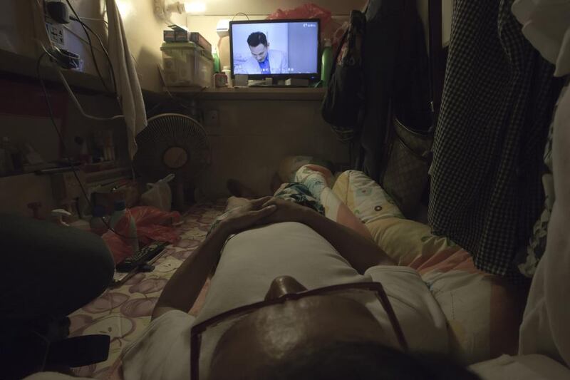 Simon Wong, an unemployed man, watches TV in his tiny home in Hong Kong.