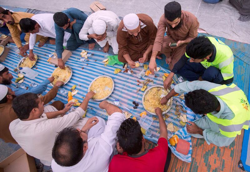 DUBAI, UNITED ARAB EMIRATES -  Workers breaking their fast. Dubai Police join hands with Berkeley Assets to serve up Iftar dinner to mark Laylatul Qadr for 10,000 labourers with seating for 5,000 and another 5,000 laborers will go home with meal boxes in Al Muhaisnah, Dubai.  Ruel Pableo for The National