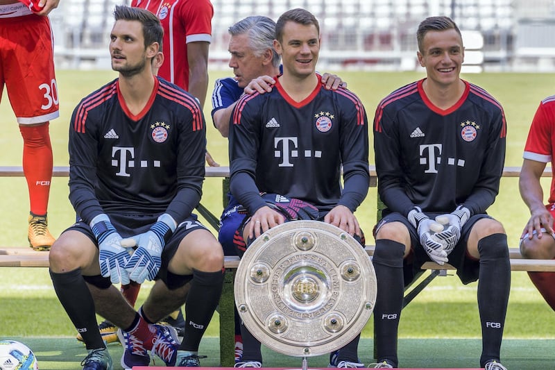 Goalkeepers of German first division Bundesliga football club FC Bayern Munich pose with the German league trophy on August 8, 2017 in Munich, southern Germany (front row, L-R) Bayern Munich's goalkeeper Sven Ulreich, Bayern Munich's goalkeeper Manuel Neuer and Bayern Munich's goalkeeper Christian Fruechtl; in background behind Neuer is seen Bayern Munich's Italian head coach Carlo Ancelotti. / AFP PHOTO / Guenter SCHIFFMANN