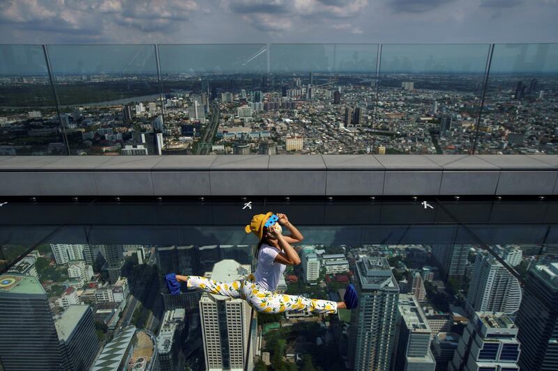 A woman observes a partial solar eclipse on the Mahanakhon Skywalk Glass Tray at the King Power Mahanakhon building in Bangkok, Thailand. Reuters