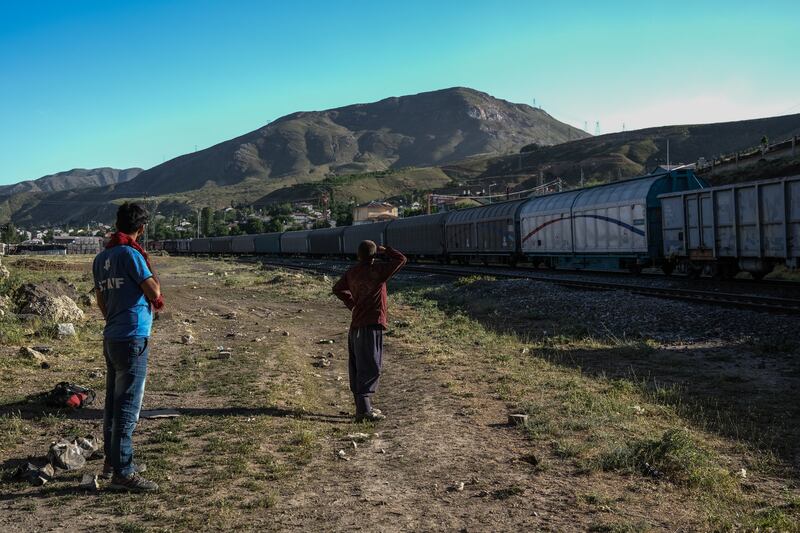 Afghans wait for the freight train to slow down under a bridge near the railway in Van city after crossing the Iran-Turkey border near Tatvan district in Bitlis city, eastern province of Turkey.