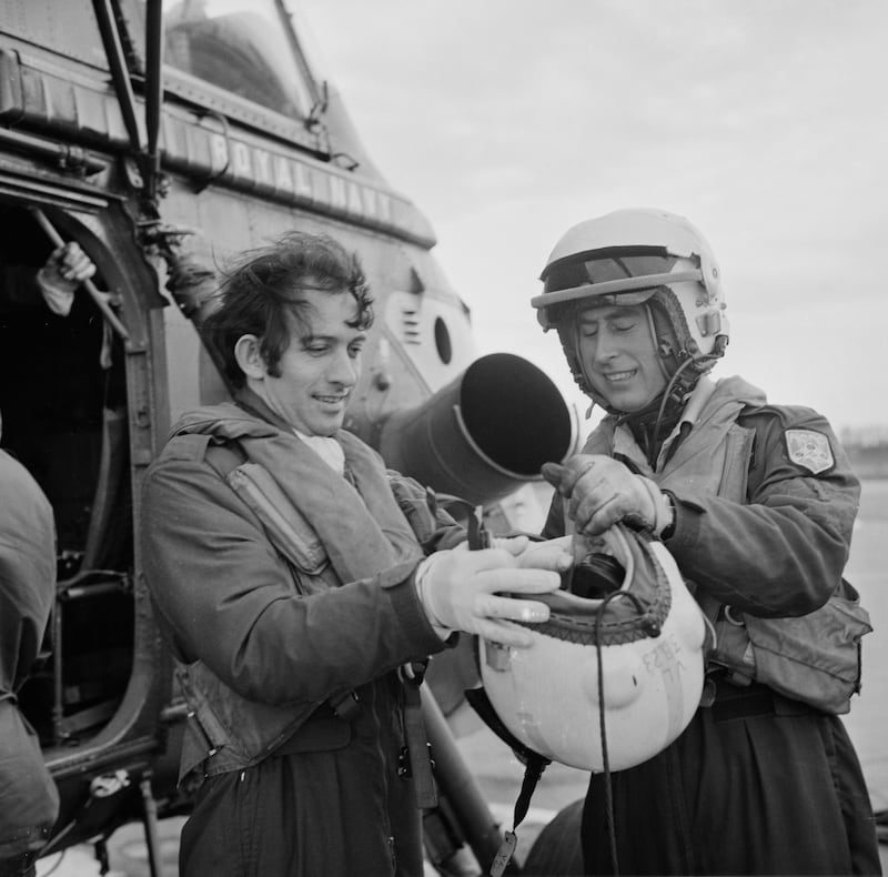 Prince Charles helps a colleague put on his helmet during his time with the 845 Naval Air Squadron in 1975