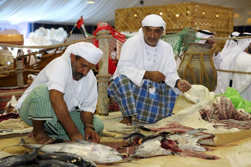 Dibba, United Arab Emirates - June 26, 2019: Mohammed Suliman Abdullah Al Dhuhoori (L) cuts up fish. Al Hosn fish salting festival. Wednesday the 26th of June 2019. Dibba. Chris Whiteoak / The National