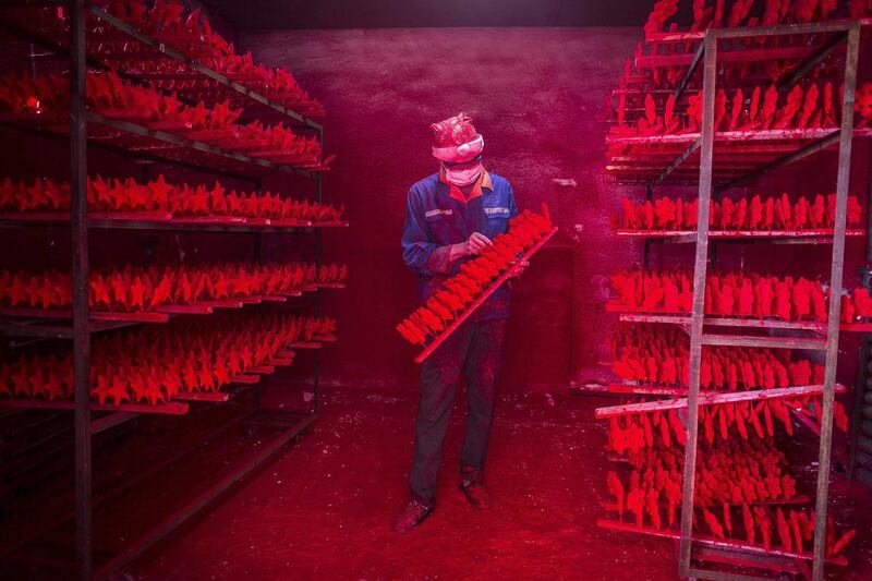 A man wearing a Christmas hat works at a factory producing Christmas decorations in Yiwu, Zhejiang province. China Daily / Reuters