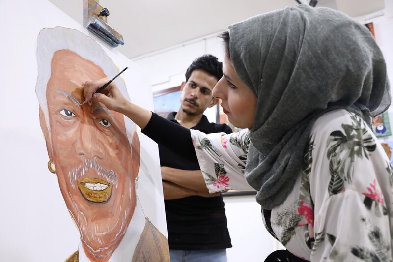 Duaa Munshid paints with her fellow artist Qasim Sulaiman an artwork depicting an American actor Morgan Freeman, in Basra, Iraq. Reuters