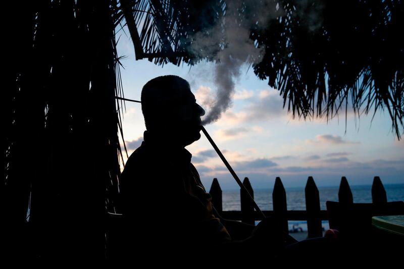 A Palestinian man smokes shisha by the beach in Gaza City. AFP