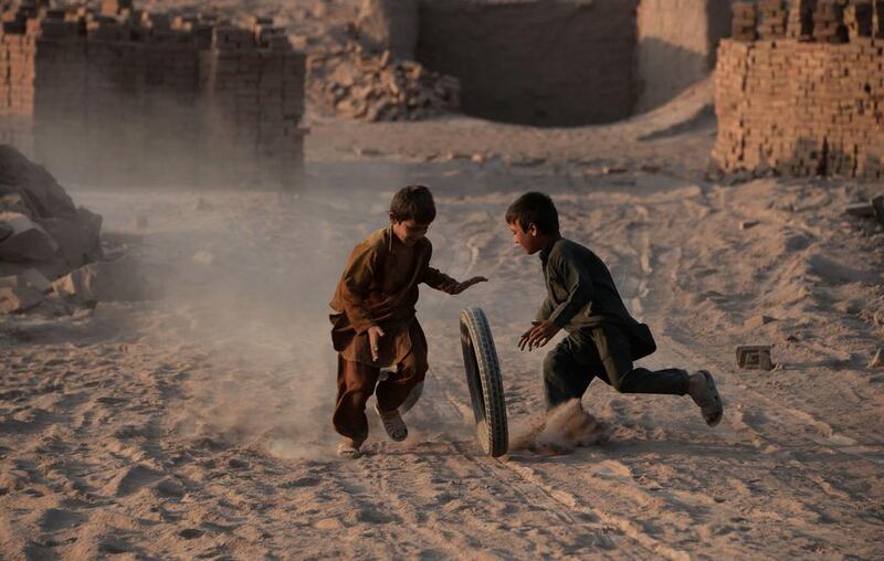 Afghan children play with a tyre on the outskirts of Jalalabad. Noorullah Shirzada / AFP Photo