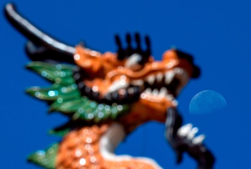 The moon is seen next to a detail of a sculpture depicting a dragon in Panama City. AFP