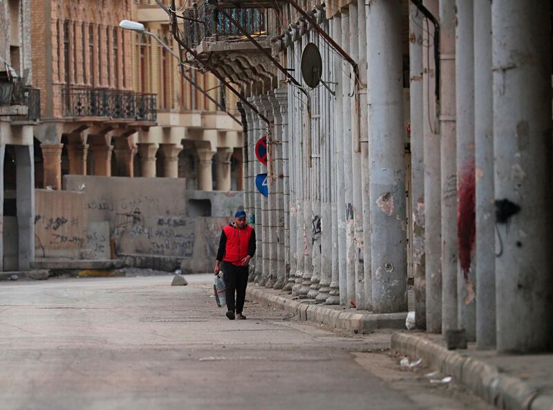 A man walks in a nearly empty street while security forces deploy to enforce a curfew to help fight the spread of the coronavirus. in central Baghdad, Iraq. AP